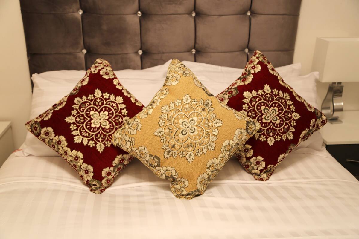 A bed with three decorative pillows and a tufted headboard.