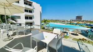 A rooftop terrace with white chairs and a table, overlooking a swimming pool and a building under construction. - Beach type pool, 10 min from the beach by Gpsrentas (Mazatlán)