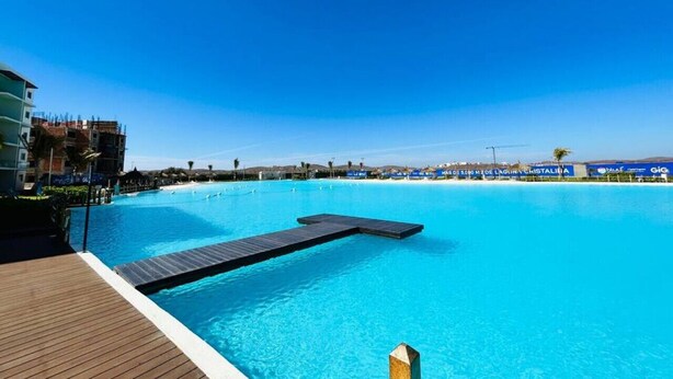 A large, clear blue pool with a wooden deck and a dock extending into the water. - Beach type pool, 10 min from the beach by Gpsrentas (Mazatlán)