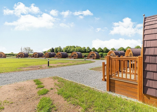 Une rangée de cabanes en bois, avec un chemin de gravier menant à un portail en bois.