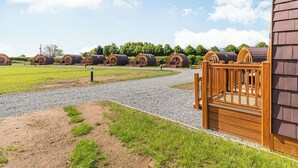 A row of wooden cabins with a gravel path leading to a wooden gate.