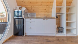 A compact kitchen with a microwave, refrigerator, and white cabinets.
