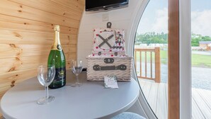 A wooden interior with a table, a bottle of champagne, two glasses, and a picnic basket.