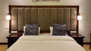 A hotel room with a large bed, two nightstands, a headboard with vertical panels, and a painting above the bed. - Hotel Barath Ladakh (Leh)