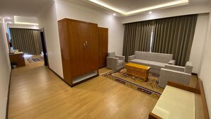 A modern living room with a wooden wardrobe, grey sofa, and a colorful rug. - Hotel Barath Ladakh (Leh)