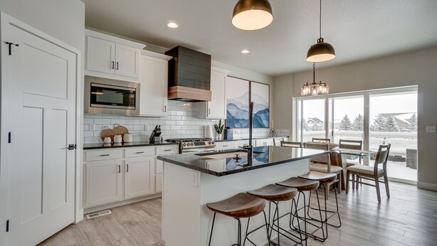 A modern kitchen with white cabinets, a stainless steel microwave, a built-in stove, and a large island with bar stools. - Family-Friendly Townhome ~ 2 Mi to Windsor Lake! (Windsor)