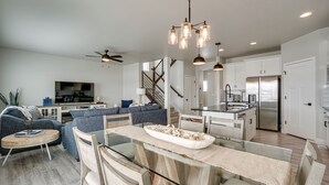 A modern kitchen with a central island, stainless steel appliances, and a dining area with a glass table. - Family-Friendly Townhome ~ 2 Mi to Windsor Lake! (Windsor)