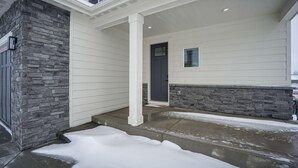 A house with a stone exterior, a front porch, and a gray door. - Family-Friendly Townhome ~ 2 Mi to Windsor Lake! (Windsor)