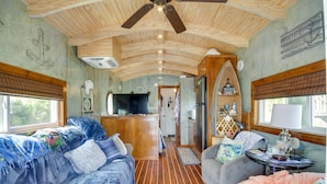 Ein gemütlicher Innenraum mit Holzbalkendecke, einer Küchenzeile und einem Wohnbereich mit Sofa und Tisch.