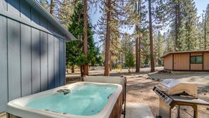 A hot tub in a wooded area with a barbecue grill nearby. - Graeagle Vacation Rental Cabin w/ Game Room! (Graeagle)