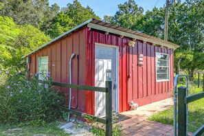 A small red wooden structure with a white door, a window, and a small porch area. - Near Lakes & Parks: Lady Lake Farm Getaway (Lady Lake)
