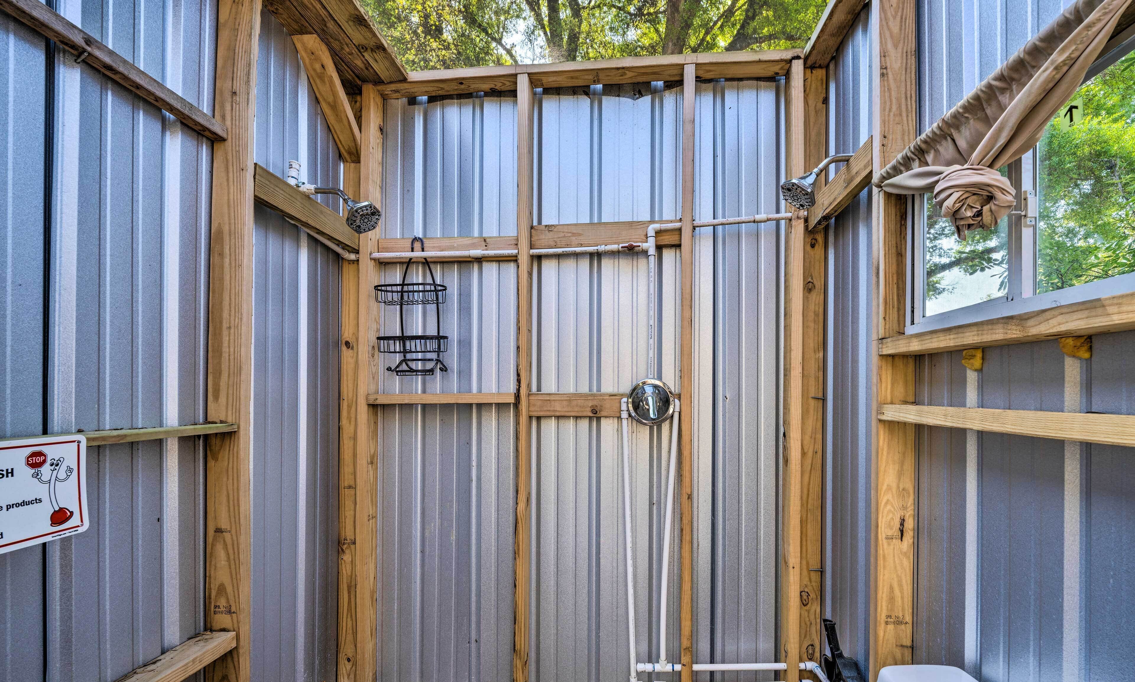 Une salle de bain aux dimensions réduites, dotée d’une structure métallique, de poutres en bois, d’une douche et d’une fenêtre.