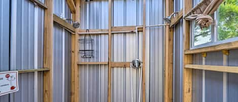 Un baño pequeño con estructura metálica, vigas de madera, ducha y ventana.