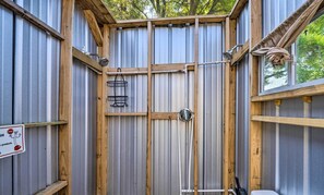 Une salle de bain aux dimensions réduites, dotée d’une structure métallique, de poutres en bois, d’une douche et d’une fenêtre.