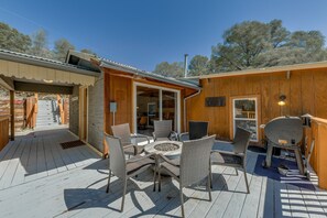 Een houten terras met rieten meubels en een barbecue.