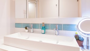 A bathroom with a white sink, a mirror, and a blue patterned tile backsplash. - Crystal Villa Ikema (Miyakojima)