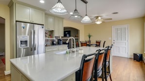 A modern kitchen with a central island, stainless steel appliances, pendant lighting, and a dining area with chairs. - Nature Getaway w/ On-Site Trails, 17 Mi to DC! (Brookeville)