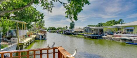 Vista del río con muelles de madera y barcos, rodeado de casas con techos de paja.