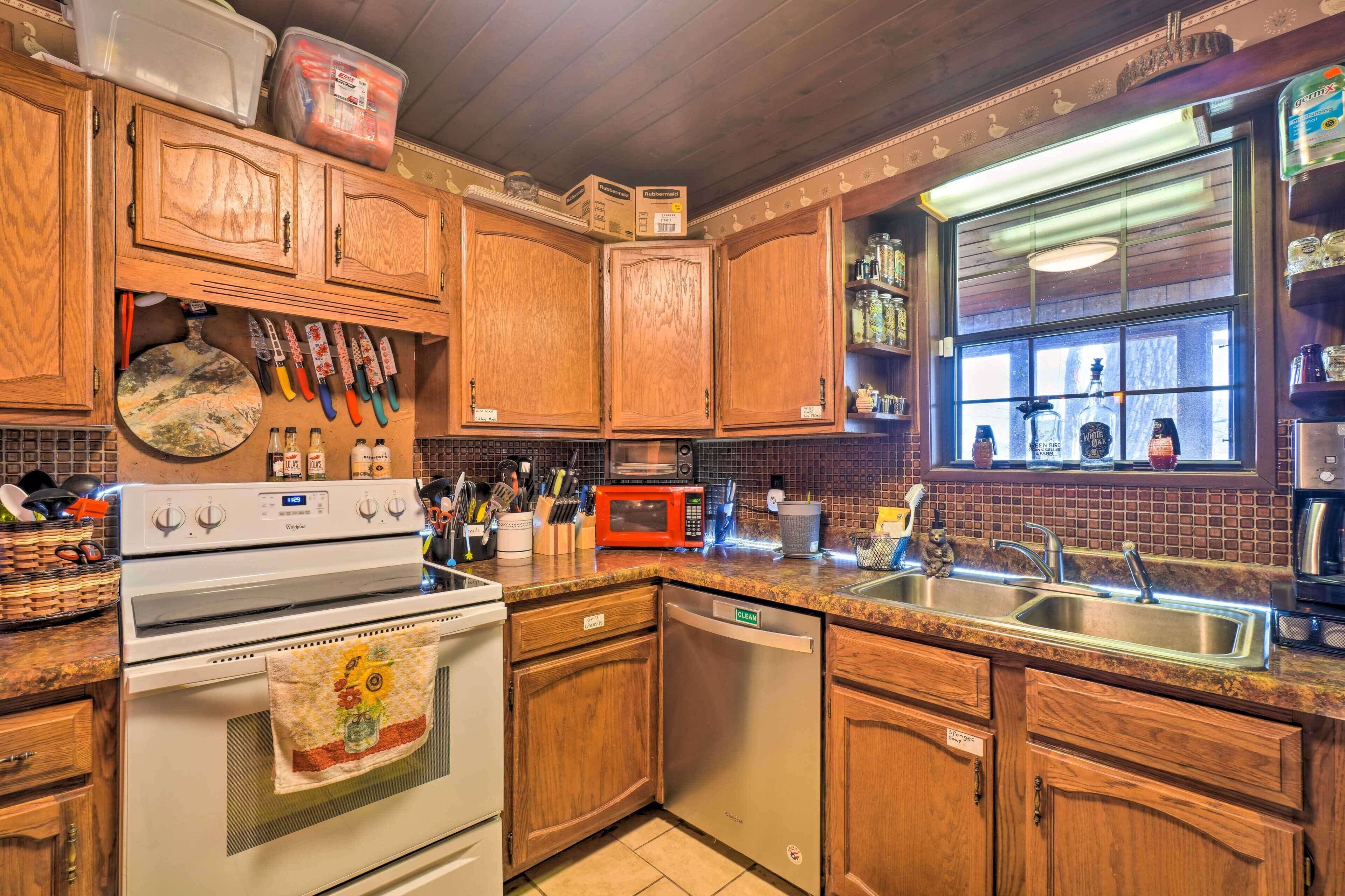 Una cocina con armarios de madera, estufa, microondas y pileta.