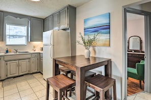 Kitchen features a central island with stools, refrigerator, sink, and window with blinds.