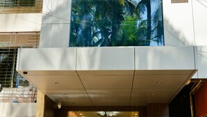 A modern building entrance with a glass door, a welcome sign, and an air conditioning unit. - Malvan's Aishwarya Hotel (Malvan)