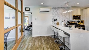 A modern kitchen with white countertops, stainless steel appliances, and a central island with bar stools. - By Joshua Tree! 'Serenity on Sage' Home w/ Hot Tub (Yucca Valley)