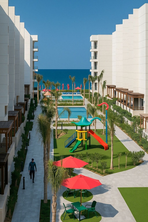 Un complexe hôtelier doté d’une piscine, de palmiers et d’un chemin menant à un bâtiment.