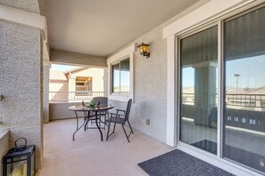 A balcony with a table and chairs, a lantern, and a large sliding glass door. - Spacious Surprise Home: Private Yard + Patio (Surprise)