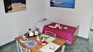 A room with a bed, a dining table with a red tablecloth, and two framed pictures on the walls. - Apartment in old Building (Santa Cesarea Terme)