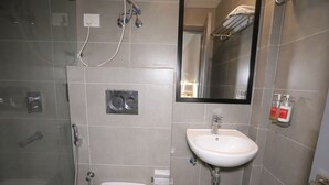 A bathroom with a shower, toilet, sink, and a mirror. - Qotel Hotel La Serene Gagan Vihar (New Delhi)