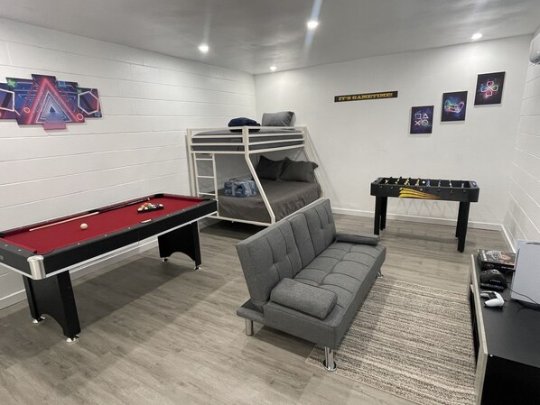 Relax in a cozy space with a bunk bed, pool table, and foosball table.
