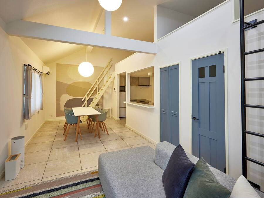 A modern apartment with a dining area, kitchen, and a staircase leading to an upper level.
