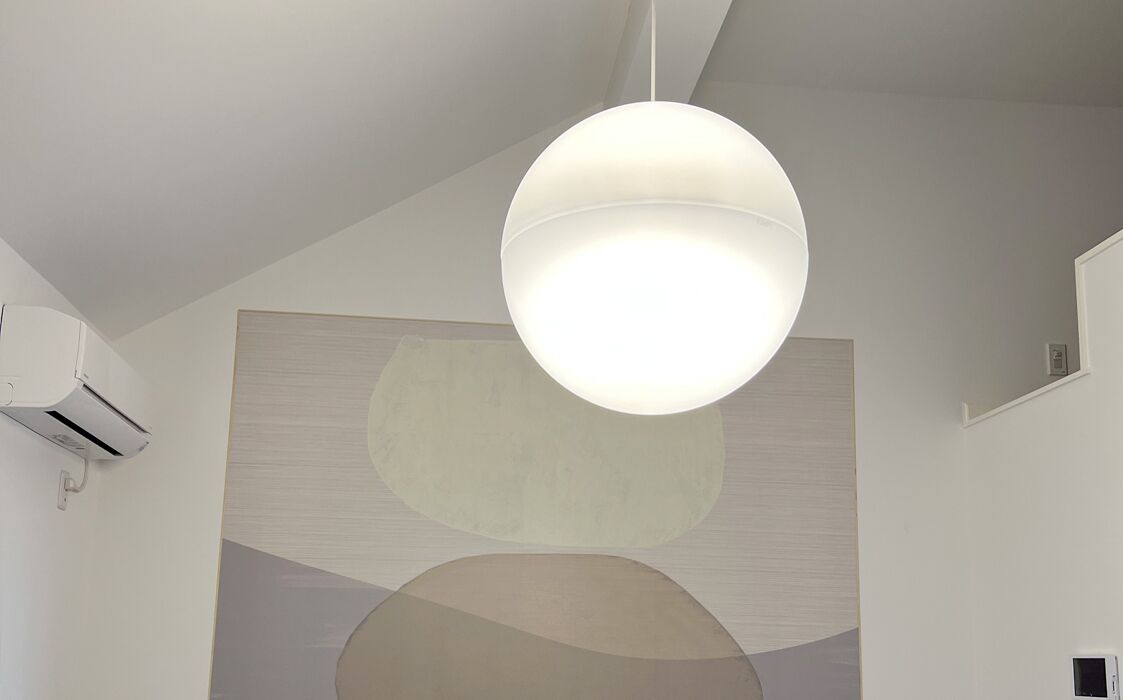 Un interior moderno con una lámpara colgante esférica, aire acondicionado instalado en la pared y arte abstracto en la pared.
