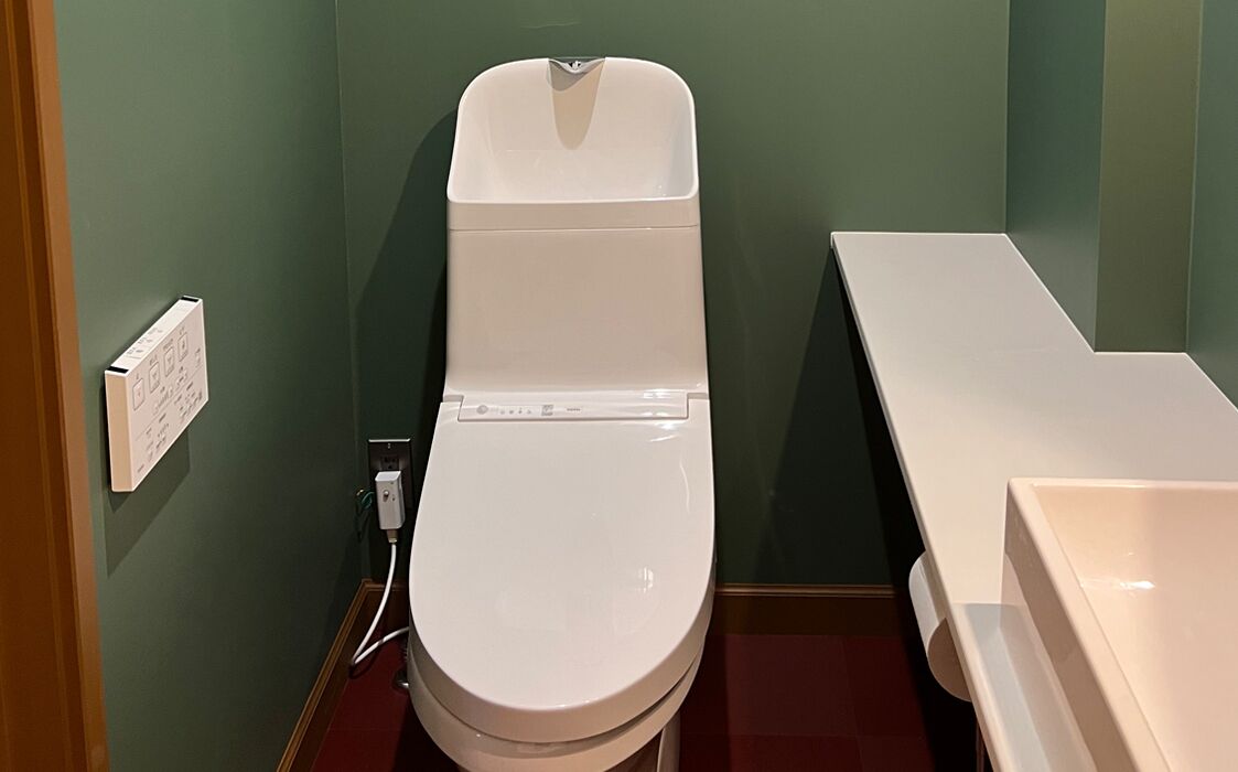 Un baño pequeño con un inodoro blanco, un lavabo blanco y una pared verde.