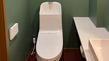 Un baño pequeño con un inodoro blanco, un lavabo blanco y una pared verde.