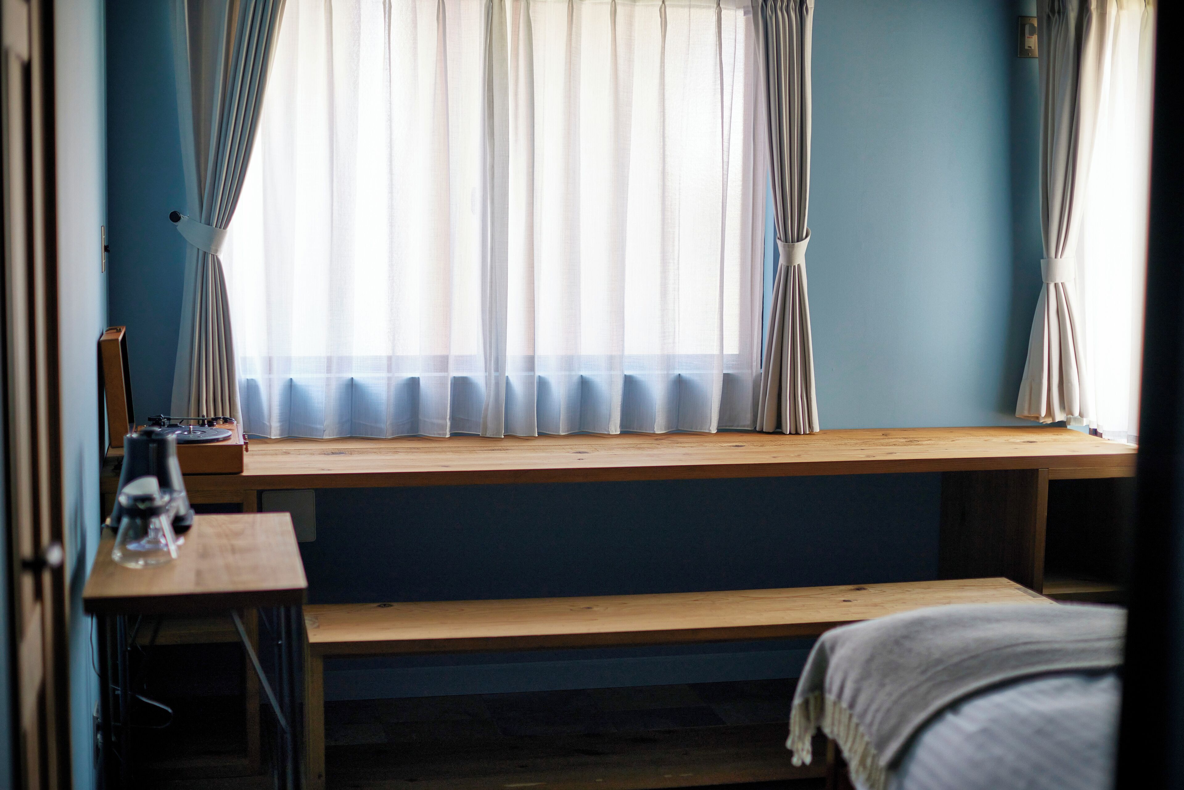 A room with a window, a wooden desk, and a bed.