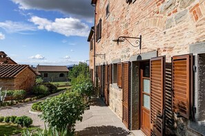 Une ruelle étroite bordée d’immeubles en pierre, de volets en bois et d’un chemin pavé.