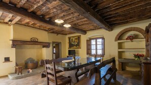 Una cuina rústica amb una illa gran, seients de fusta i un paviment de pedra.