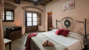 Un dormitori amb un llit, un taulell de fusta, una finestra i una porta.