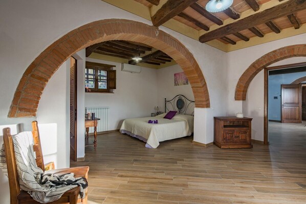 A bedroom with a bed, wooden furniture, and a brick archway.