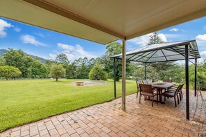 Enjoy dining or socializing in this serene outdoor space surrounded by lush greenery and a beautiful view.