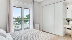 A bedroom with a large bed, a sliding glass door to a balcony, a wardrobe, and a small table with a vase of flowers. - Sanders Old Port - Precious 1-bdr. Apt. w/ Balcony (Thessaloniki)