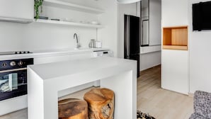 A modern kitchen with white cabinetry, a black stove, and a wooden island. There are pendant lights above the island and a plant on the wall. - Sanders Old Port - Precious 1-bdr. Apt. w/ Balcony (Thessaloniki)
