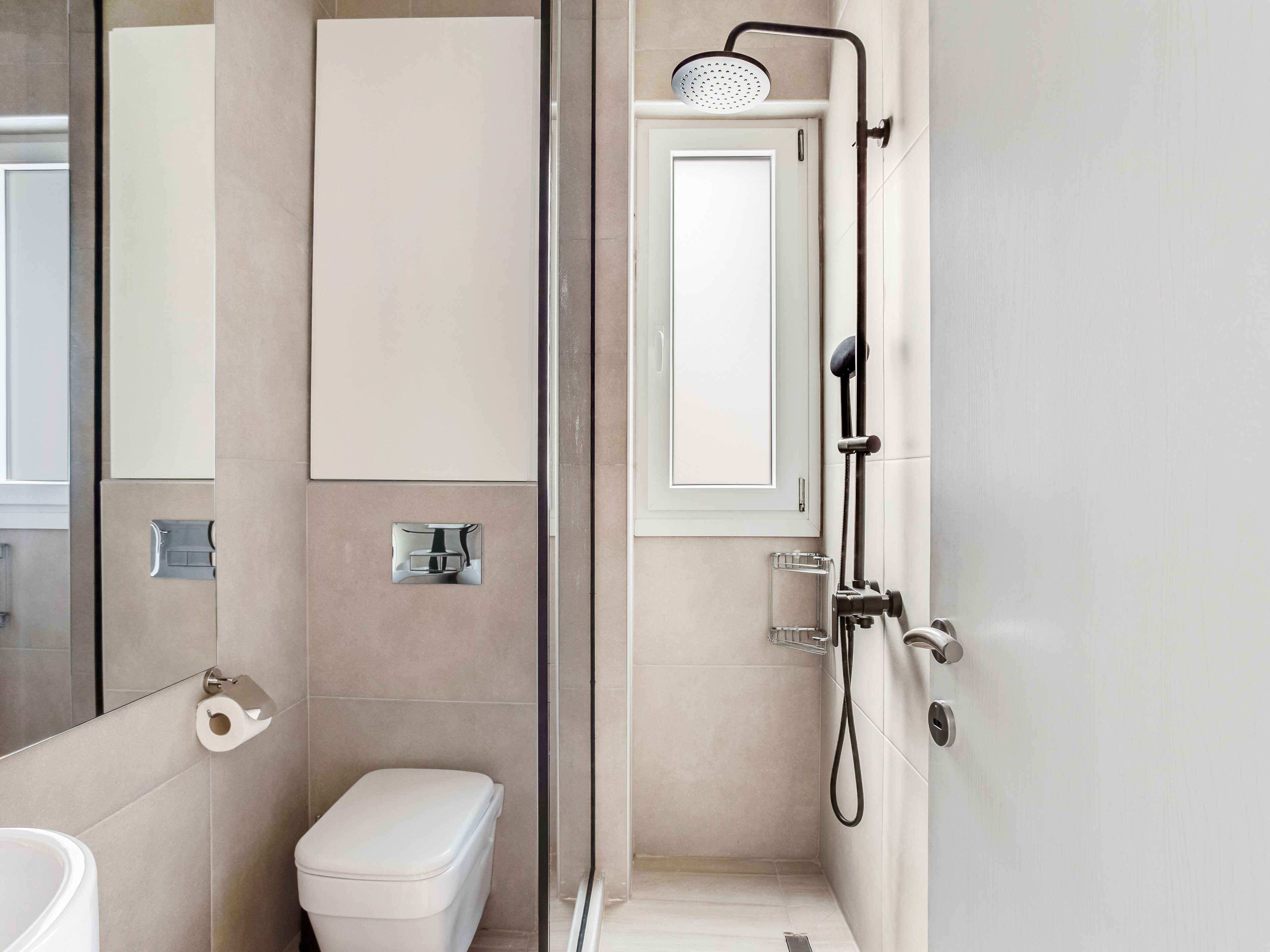 A modern bathroom with a toilet, a shower, and a mirror.