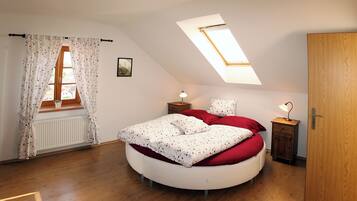 Un dormitorio con tragaluces, una cama redonda, un radiador y suelo de madera.