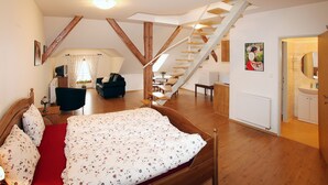 A bedroom with a wooden bed, a red carpet, a staircase, and a bathroom with a sink and mirror. - Penzion u Chodského Hradu (Domazlice)