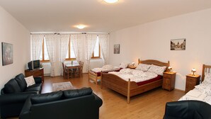 A bedroom with a wooden bed, a black leather sofa, a wooden desk, and a chair. - Penzion u Chodského Hradu (Domazlice)