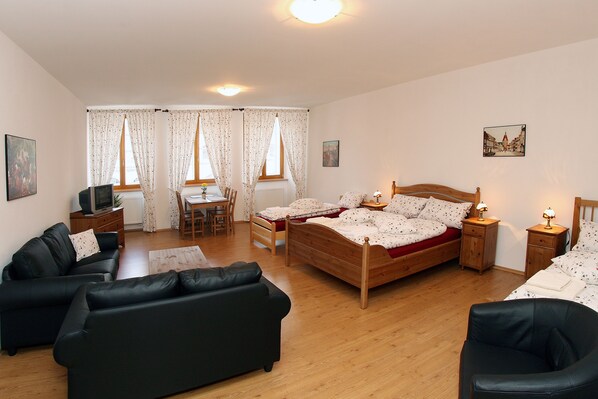 A bedroom with a wooden bed, a black leather sofa, a wooden desk, and a chair. - Penzion u Chodského Hradu (Domazlice)