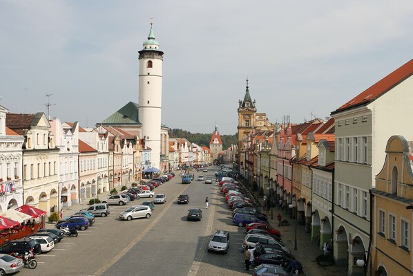 Eine Straße mit parkenden Autos und historischen Gebäuden, darunter ein markanter Turm.