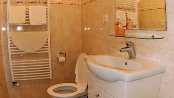 Une salle de bain équipée de toilettes, d’un lavabo et d’un porte-serviettes.